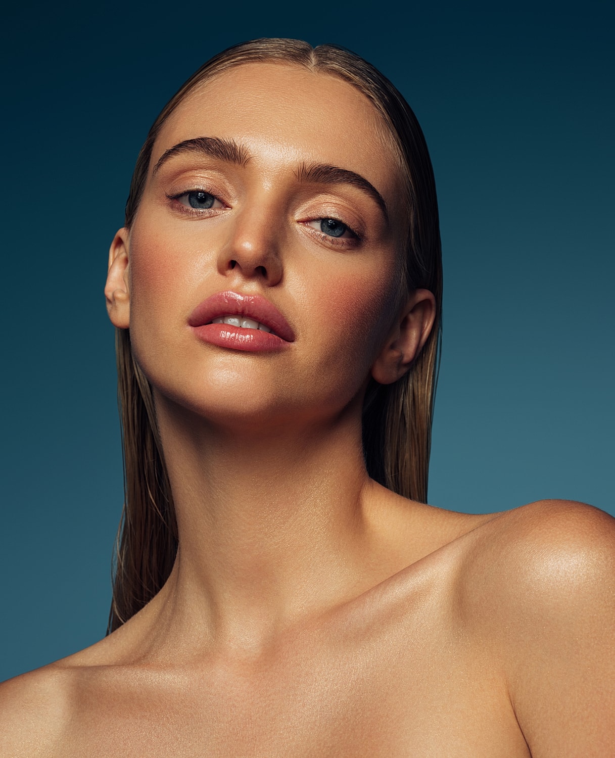 Close-up portrait of a woman with glossy skin.